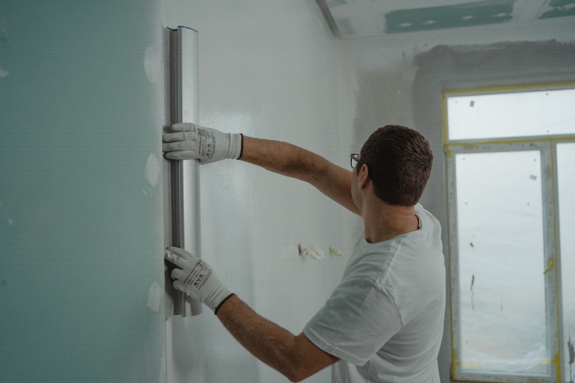 Plasterer running a feathering tool down a freshly skimmed interior wall